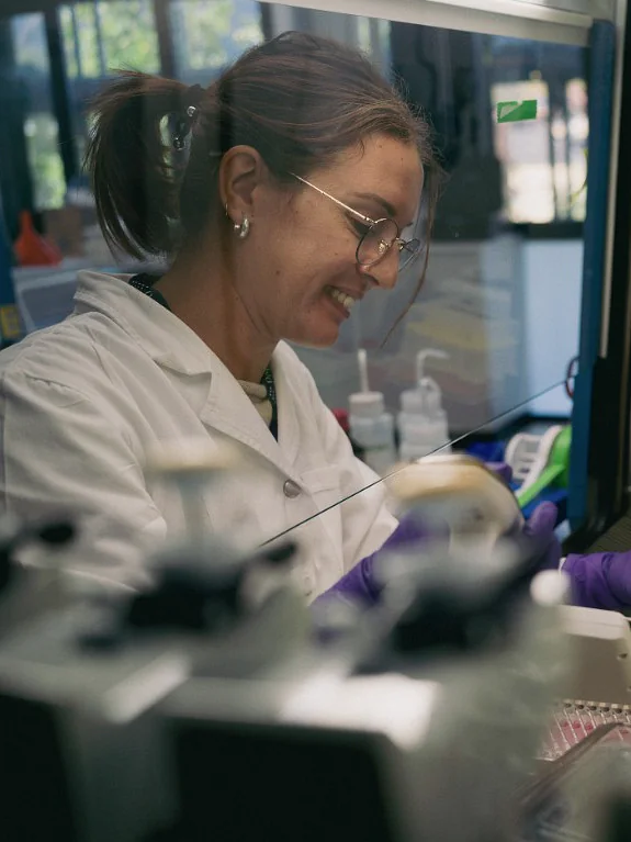A Peptone scientist smiling while preparing samples at a laboratory bench