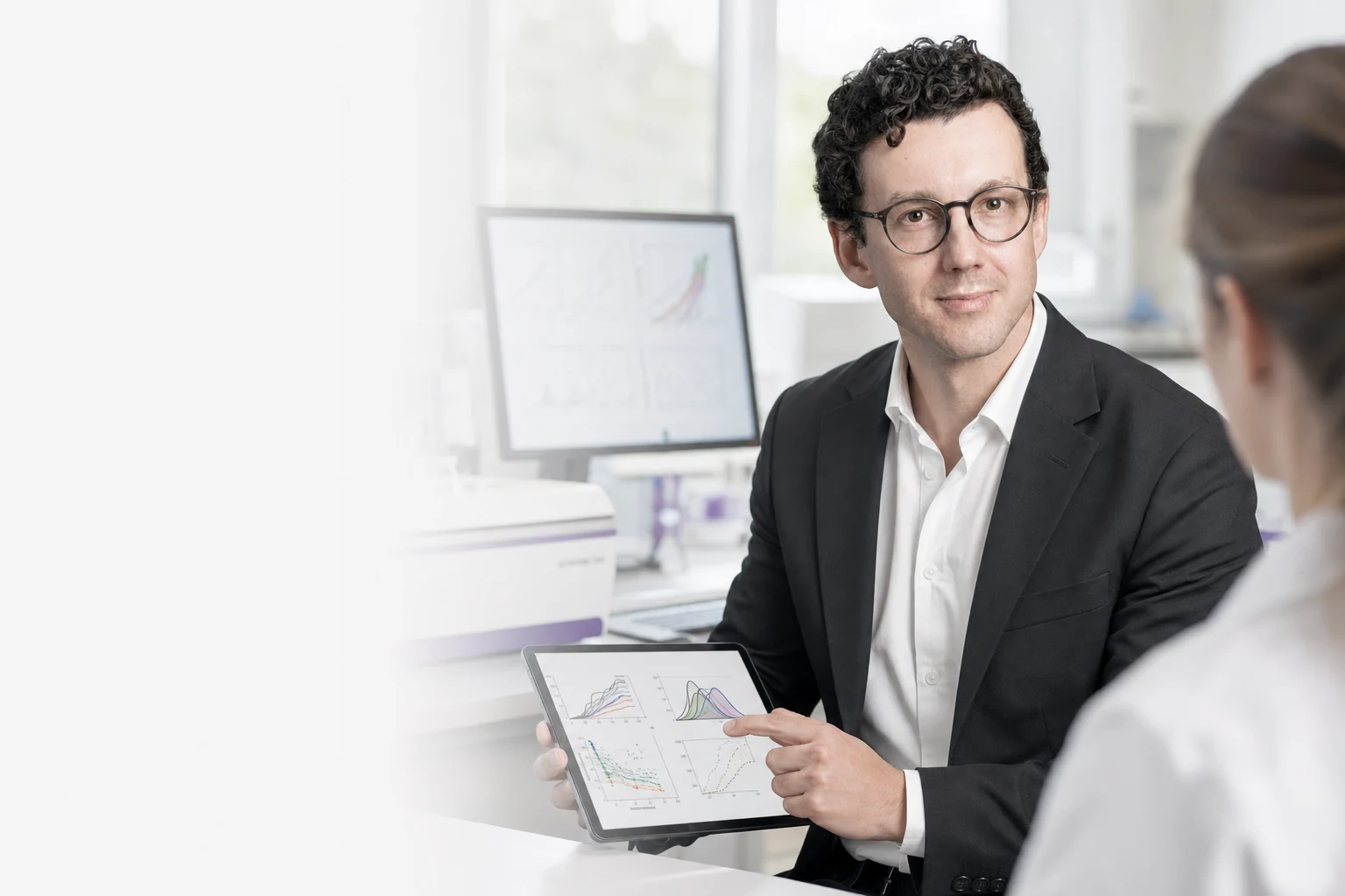 Dr. Kamil Tamiola reviewing protein-characterization results with a colleague in a bright laboratory. Illustrative generated image based on an approved Peptone team portrait.