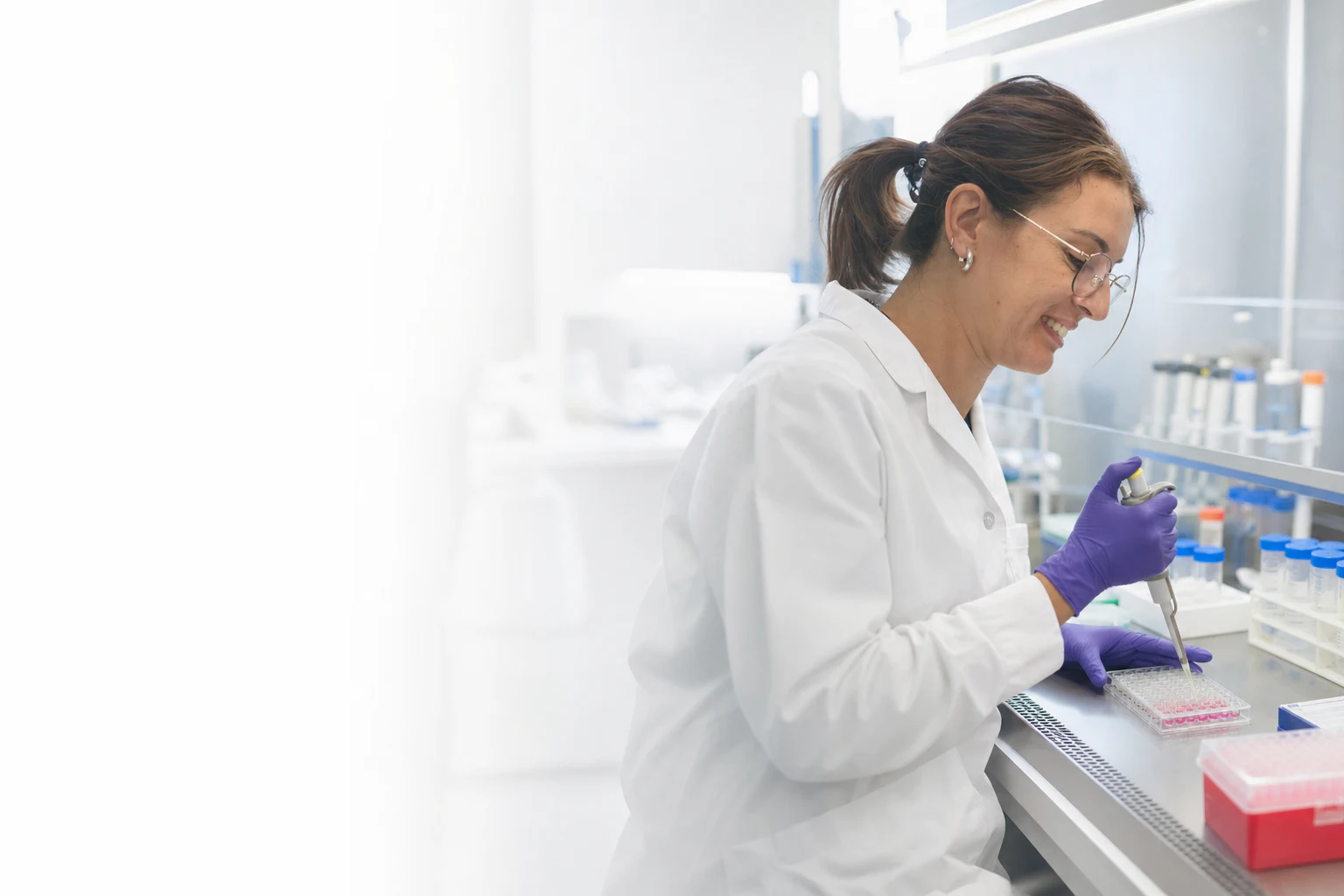A Peptone scientist pipetting samples into a 96-well plate in a bright laboratory. Illustrative generated image based on a Peptone team photograph.