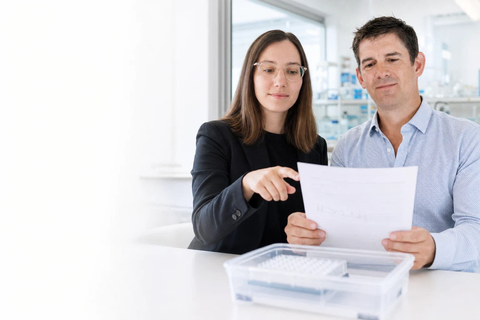 Two Peptone team members reviewing a 96-well assay plate and printed result in a bright laboratory. Illustrative generated image based on Peptone team portraits.